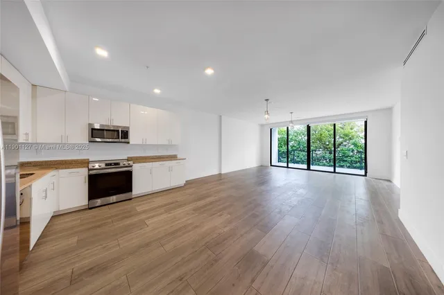 a large kitchen with granite countertop a large counter top stainless steel appliances and cabinets