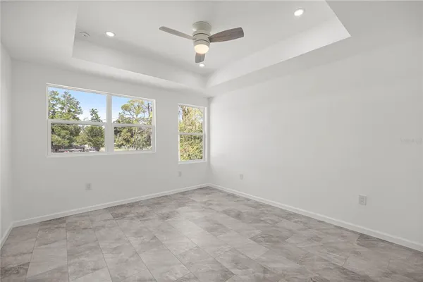 an empty room with windows and ceiling fan