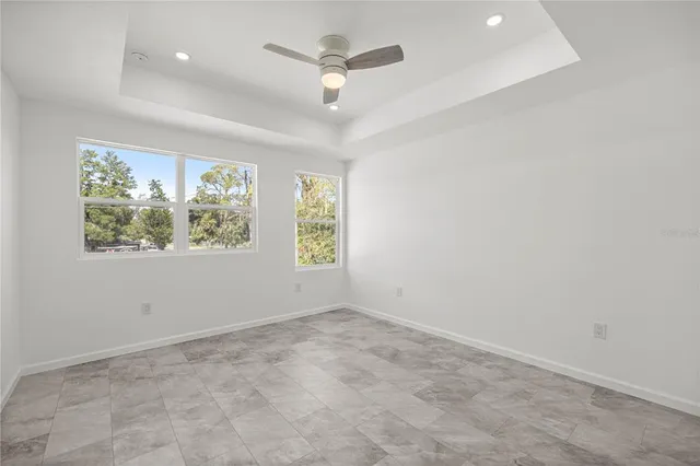 an empty room with windows and ceiling fan