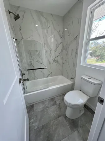 a white toilet sitting next to a bath tub
