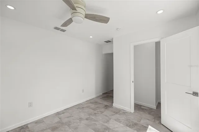 an empty room with a ceiling fan and carpet