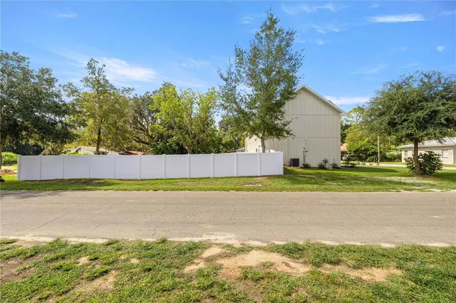a view of a house with a yard and a large tree