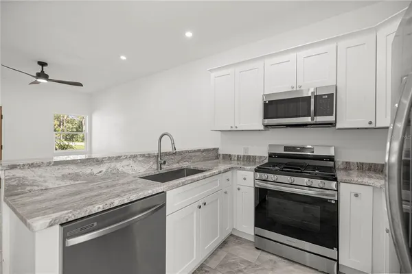a kitchen with granite countertop a sink and a stove top oven with wooden floor