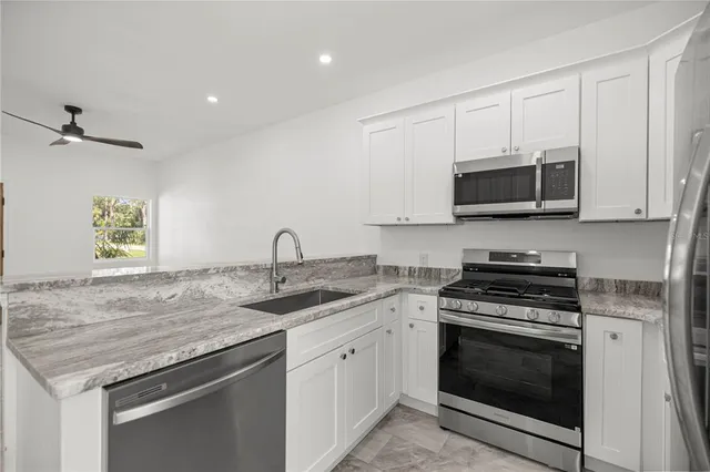 a kitchen with granite countertop a sink and a stove top oven with wooden floor