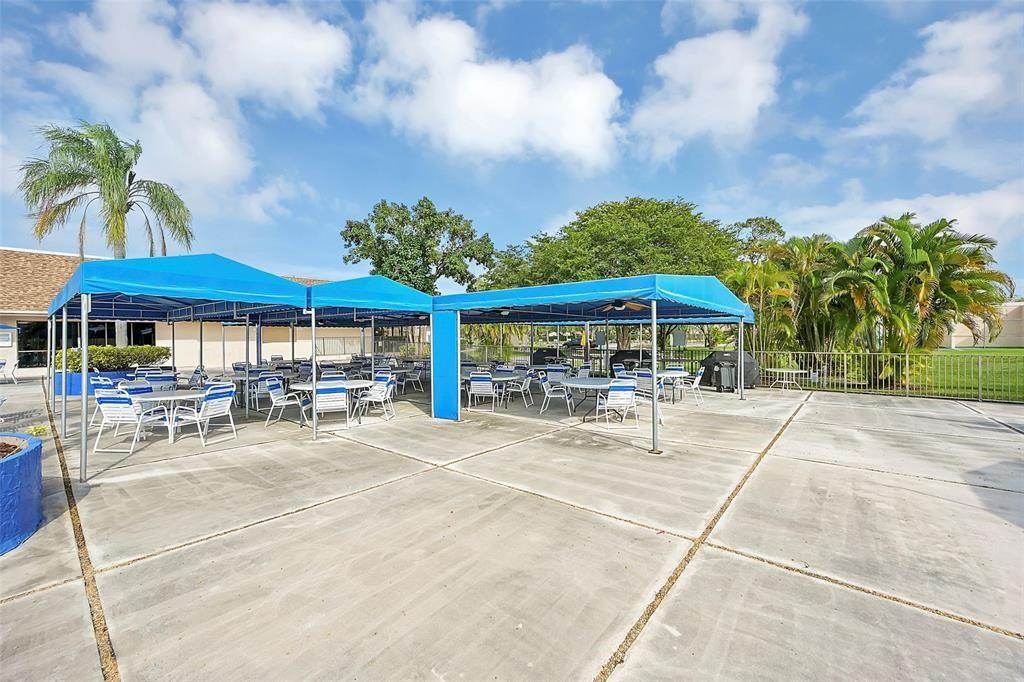 2541 North Nob Hill Road, Unit 206 Sunrise, FL 33322 - Photo 32 of 44 a view of a patio with a table and chairs under an umbrella with palm trees