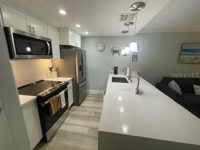 a kitchen with stainless steel appliances a stove a microwave and white cabinets