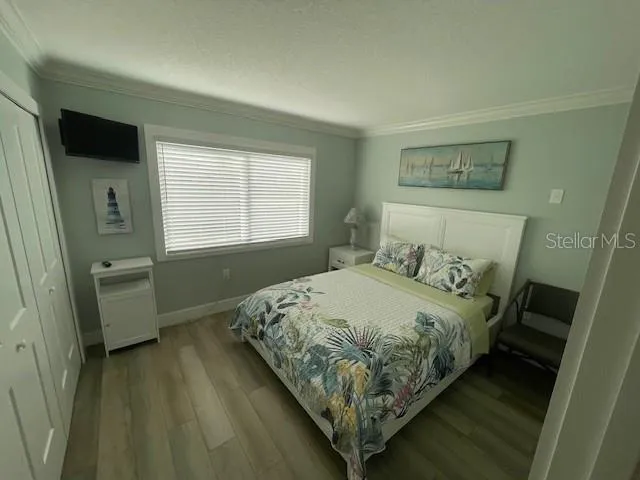 a bedroom with a bed and a flat tv screen on the dresser