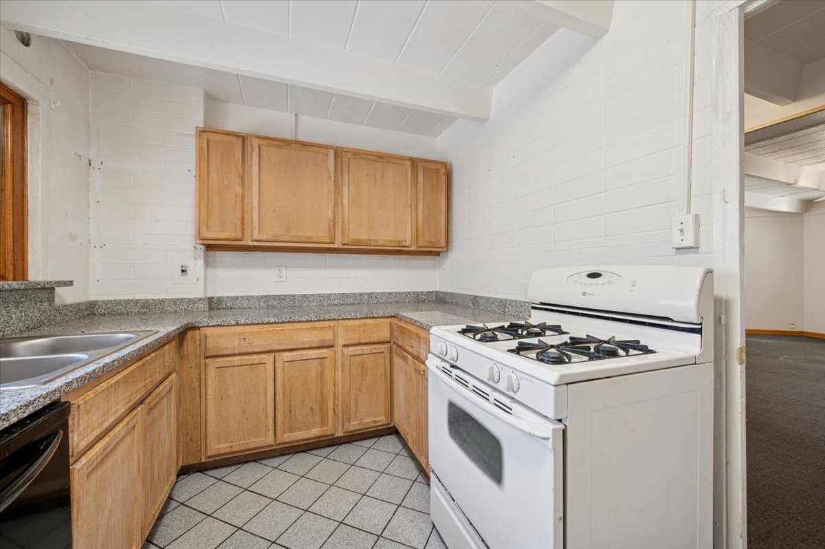 1140 West Lunt Avenue, Unit 1B Chicago, IL 60626 - Photo 6 of 13 a white kitchen with granite countertop stainless steel appliances stove top oven and sink