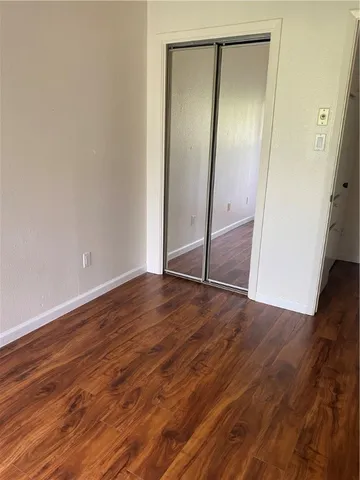 an empty room with wooden floor and mirror