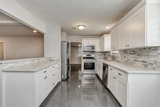 a kitchen with granite countertop white cabinets and white stainless steel appliances