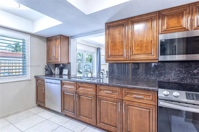a kitchen with granite countertop wooden cabinets stainless steel appliances a sink and a window