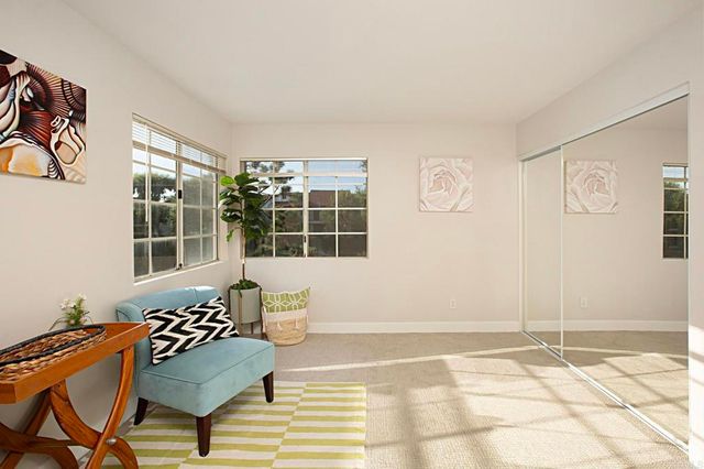 a living room with a black white checkered floor with couches and a dining table with garden view