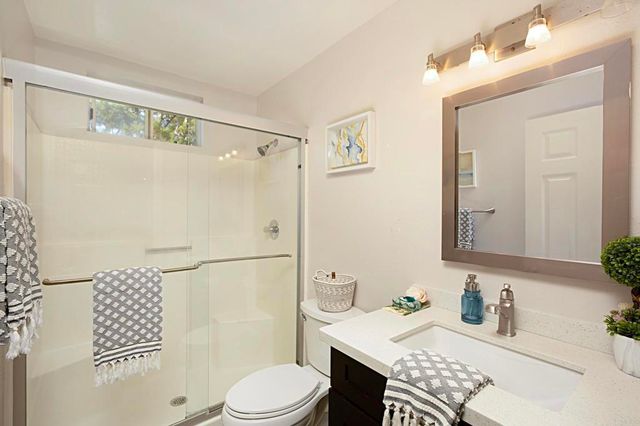 a bathroom with a granite countertop sink toilet a mirror a vanity and shower