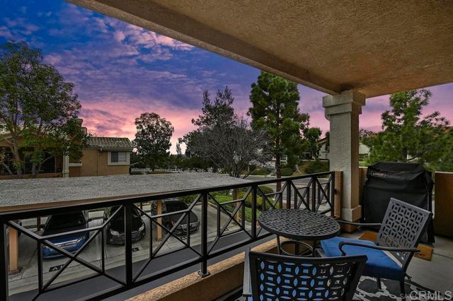 a balcony with wooden floor potted plants and a floor to ceiling window
