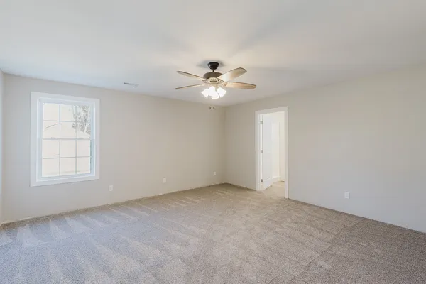 an empty room with chandelier fan and windows