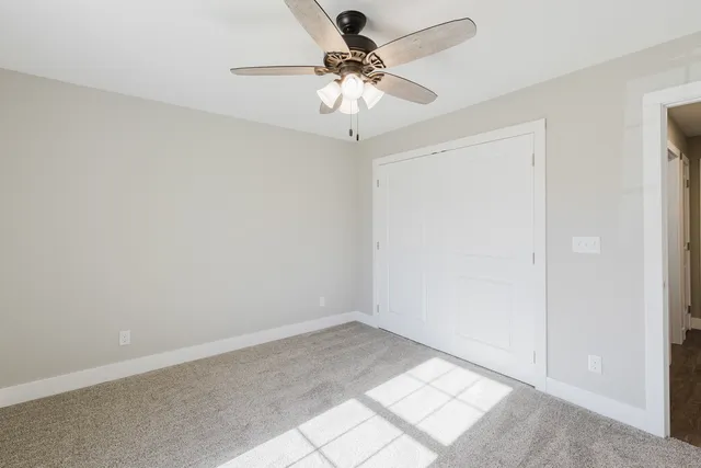 wooden floor in an empty room with a chandelier fan