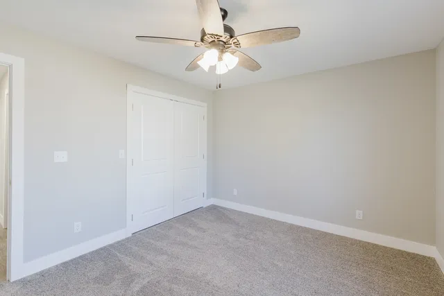 an empty room with a chandelier fan and windows