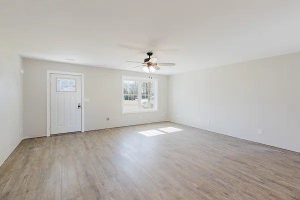 an empty room with wooden floor chandelier and windows