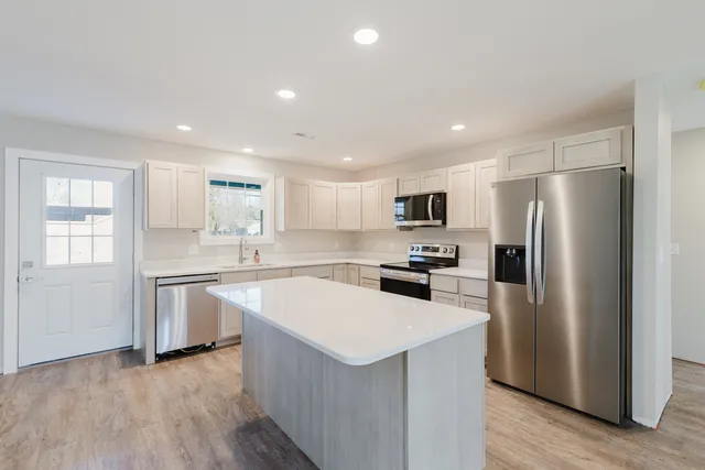 a kitchen with a refrigerator a sink dishwasher with a stove and wooden floor