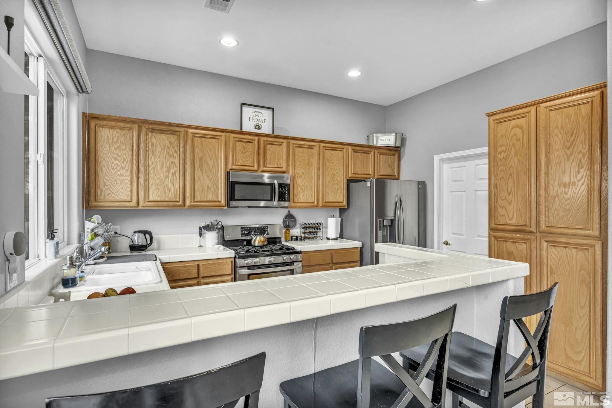 10518 French Meadows Way Reno, NV 89521 - Photo 31 of 34 a kitchen with stainless steel appliances a stove a sink dishwasher and a refrigerator with wooden floor