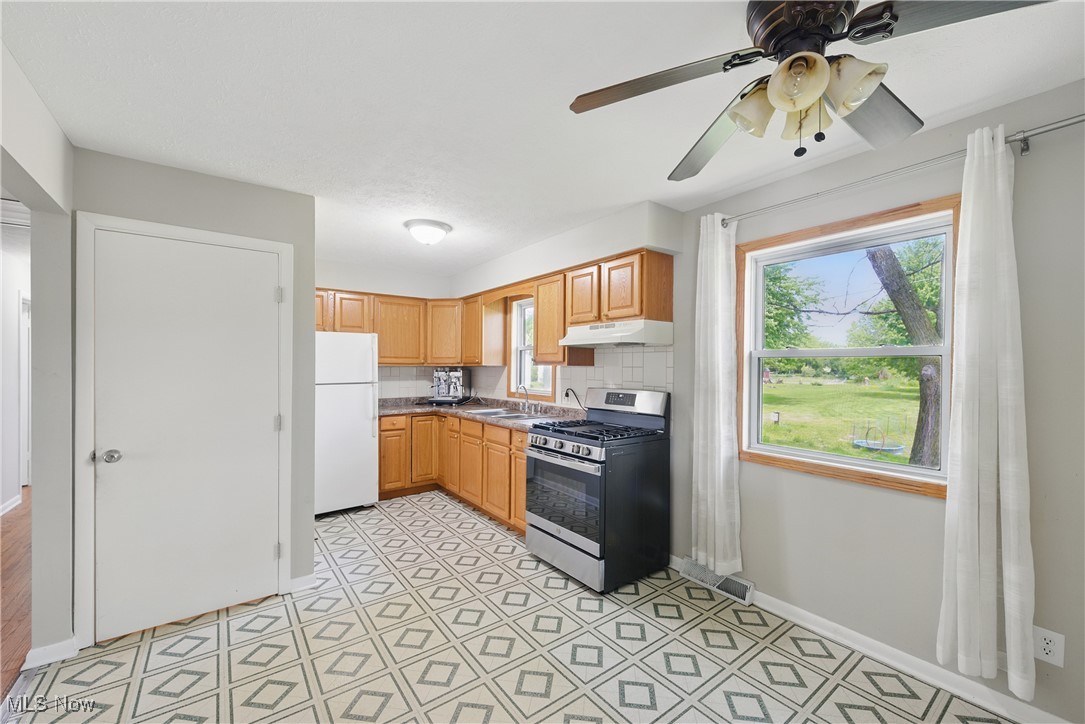 7835 Elyria Road Medina, OH 44256 - Photo 25 of 46 Kitchen with gas stove, under cabinet range hood, freestanding refrigerator, baseboards, and ceiling fan