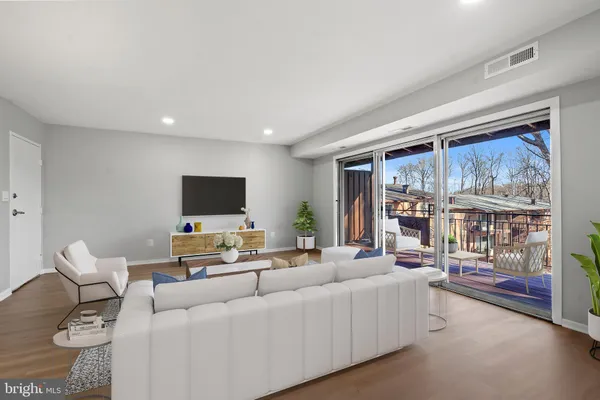 a living room with furniture a flat screen tv and a floor to ceiling window