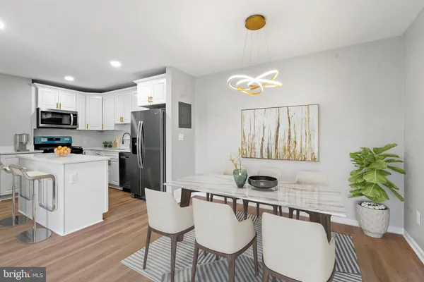 a kitchen with a refrigerator a stove a microwave a dining table and chairs with wooden floor