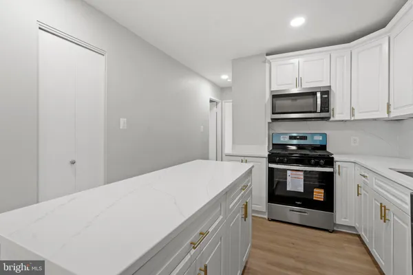 a kitchen with stainless steel appliances a stove a microwave and white cabinets