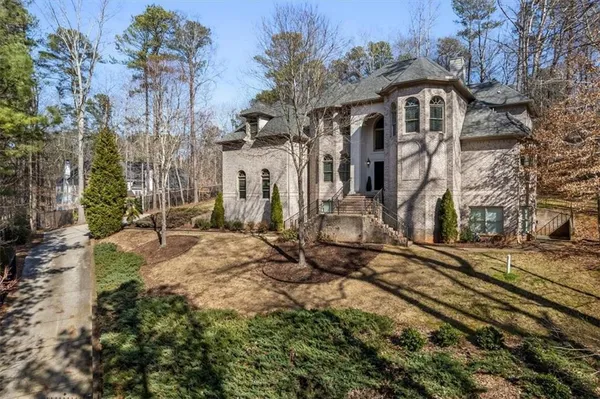 a view of a white house next to a road with large trees