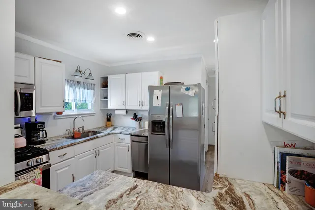 a kitchen with stainless steel appliances kitchen island granite countertop a refrigerator sink and cabinets