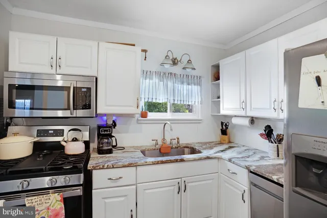 a kitchen with granite countertop a sink a stove and cabinets