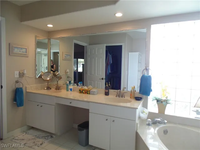 a bathroom with a double vanity sink mirror and bathtub