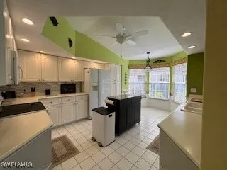 a large kitchen with kitchen island a counter top space a sink a refrigerator and a large window
