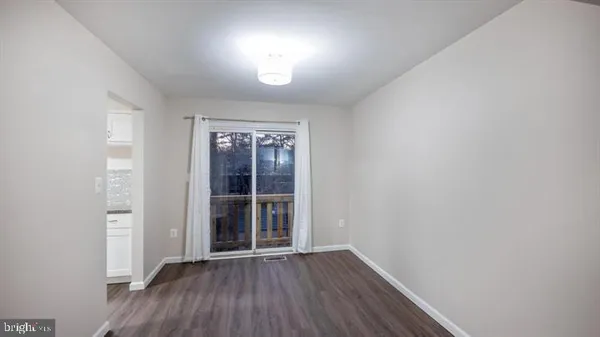 an empty room with wooden floor and window