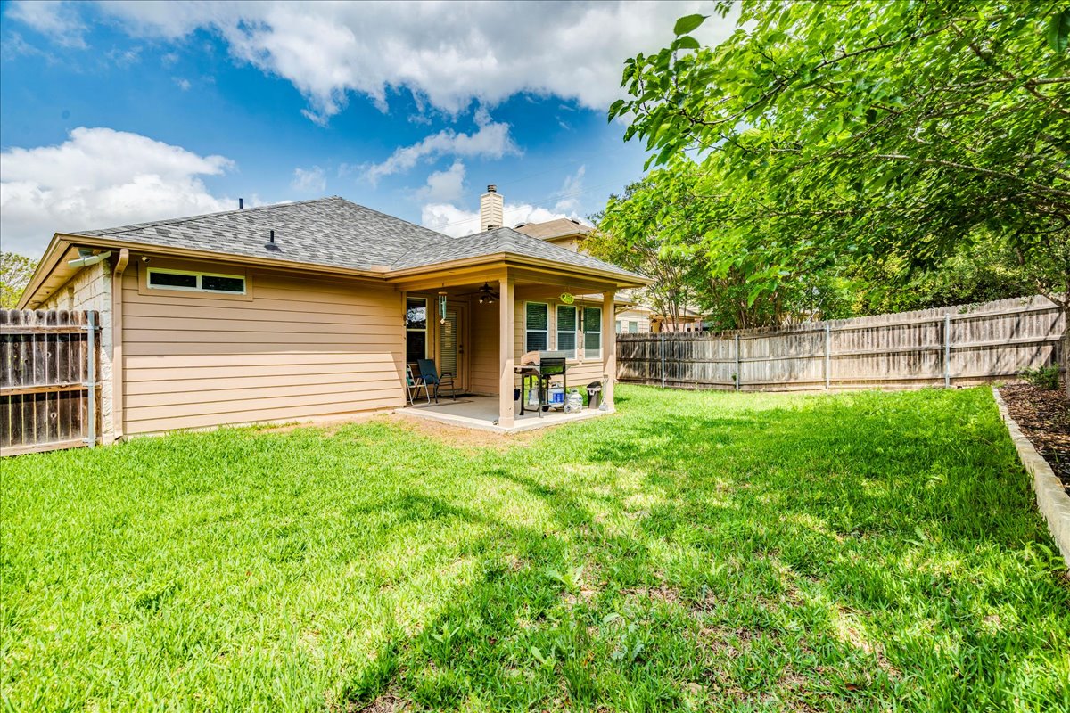 1151 Stone Rim Loop Buda, TX 78610 - Photo 29 of 36 The property features a spacious lawn, a covered patio area, and a privacy fence