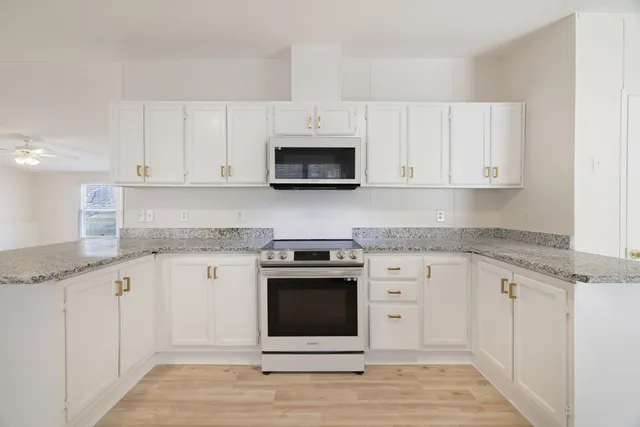 a kitchen with granite countertop white cabinets and stainless steel appliances