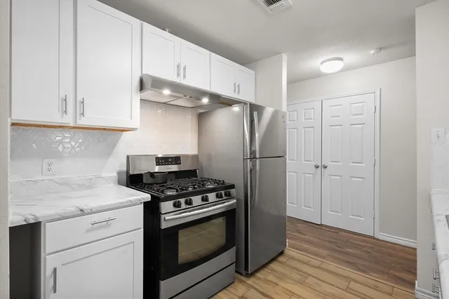a kitchen with stainless steel appliances white cabinets and a stove top oven