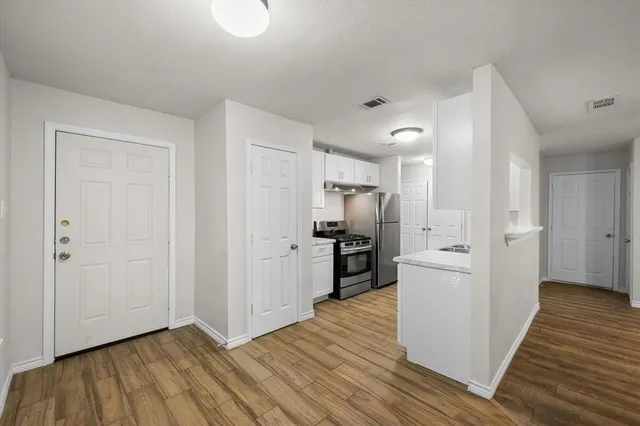 a view of a kitchen with refrigerator and wooden floor