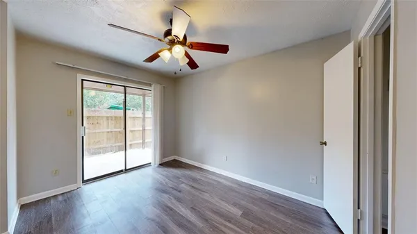 an empty room with wooden floor fan and windows