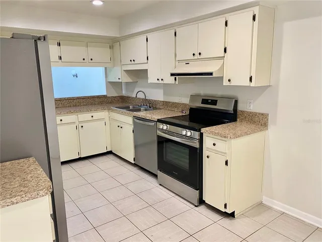a kitchen with granite countertop white cabinets white stainless steel appliances and a sink