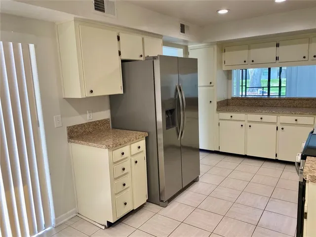 a kitchen with white cabinets and refrigerator