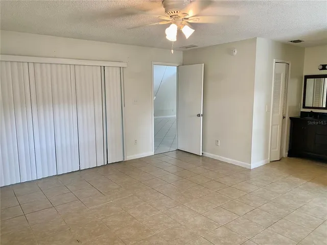 an empty room with windows and fan