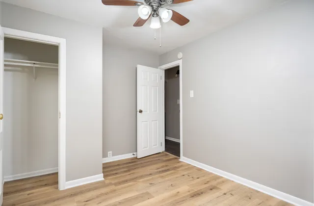 an empty room with wooden floor closet and windows