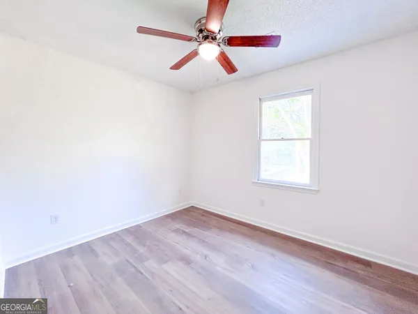 an empty room with windows and fan