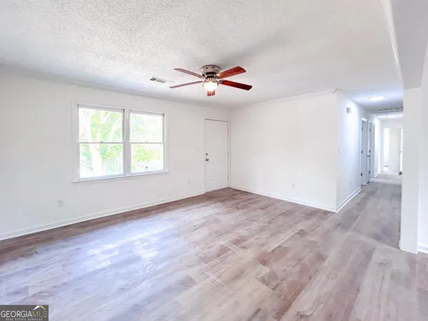 an empty room with windows and ceiling fan