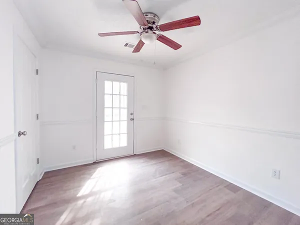 an empty room with chandelier fan and windows