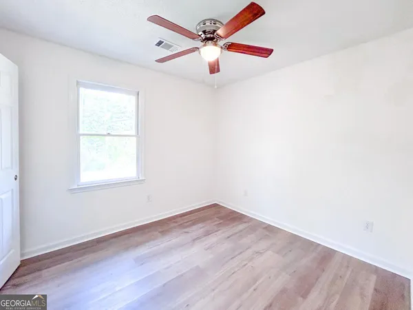 an empty room with a window and a fan