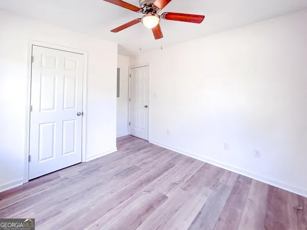an empty room with wooden floor fan and windows