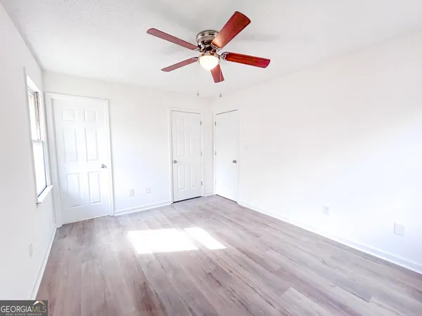 an empty room with wooden floor fan and windows