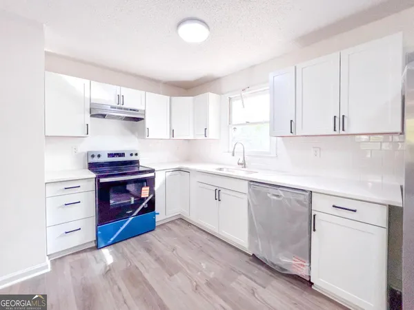a kitchen with stainless steel appliances sink cabinets and wooden floor